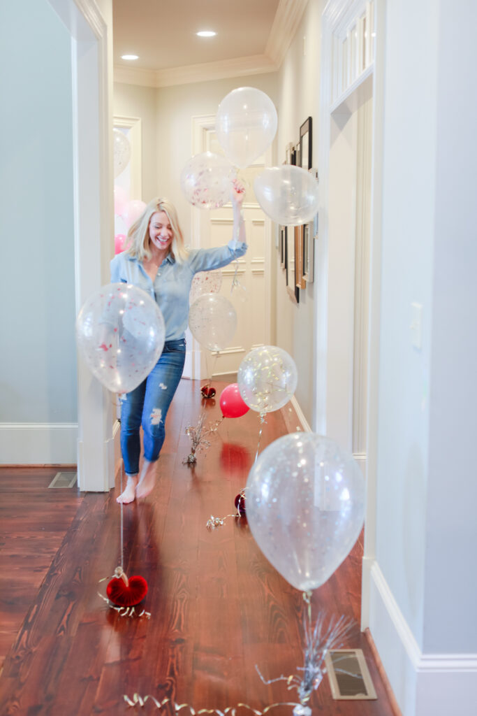 A hallway with Dear Elly writer, Kelly Page, holding a balloon showing simple birthday morning ideas for kids.