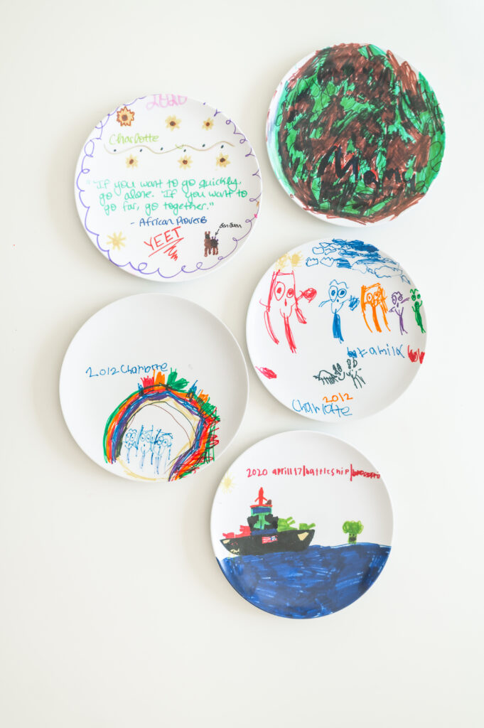 A post about ideas for celebrating kids without big parties uses custom decorated plates. Five plates are laid out, each with kid drawings on them to show custom ideas for dinners.
