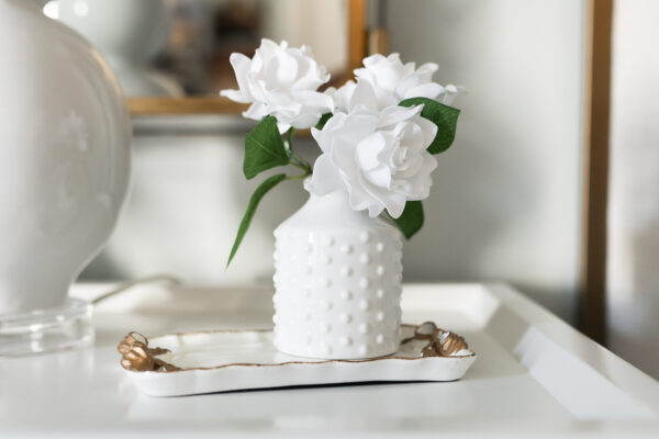 White flower vase with gardenia flowers on a bedside table show simple traditions that don’t cost money.