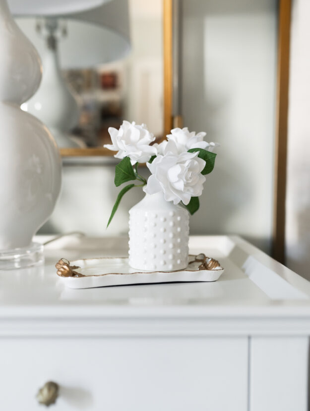 White flower vase with gardenia flowers on a bedside table show simple traditions that don’t cost money.