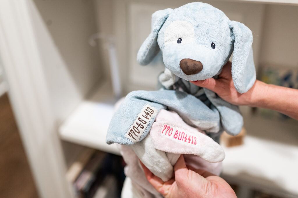 A kids lovey puppy is embroidered with phone number for a post about how to label a child’s stuffed animal.