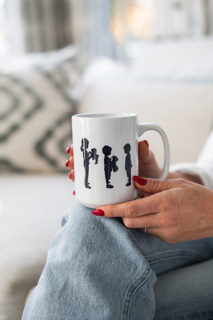 Sentimental coffee gifts for dads from kids - a photo of cardboard silhouettes of three children printed on a white mug held by Dear Elly creator Kelly Page.